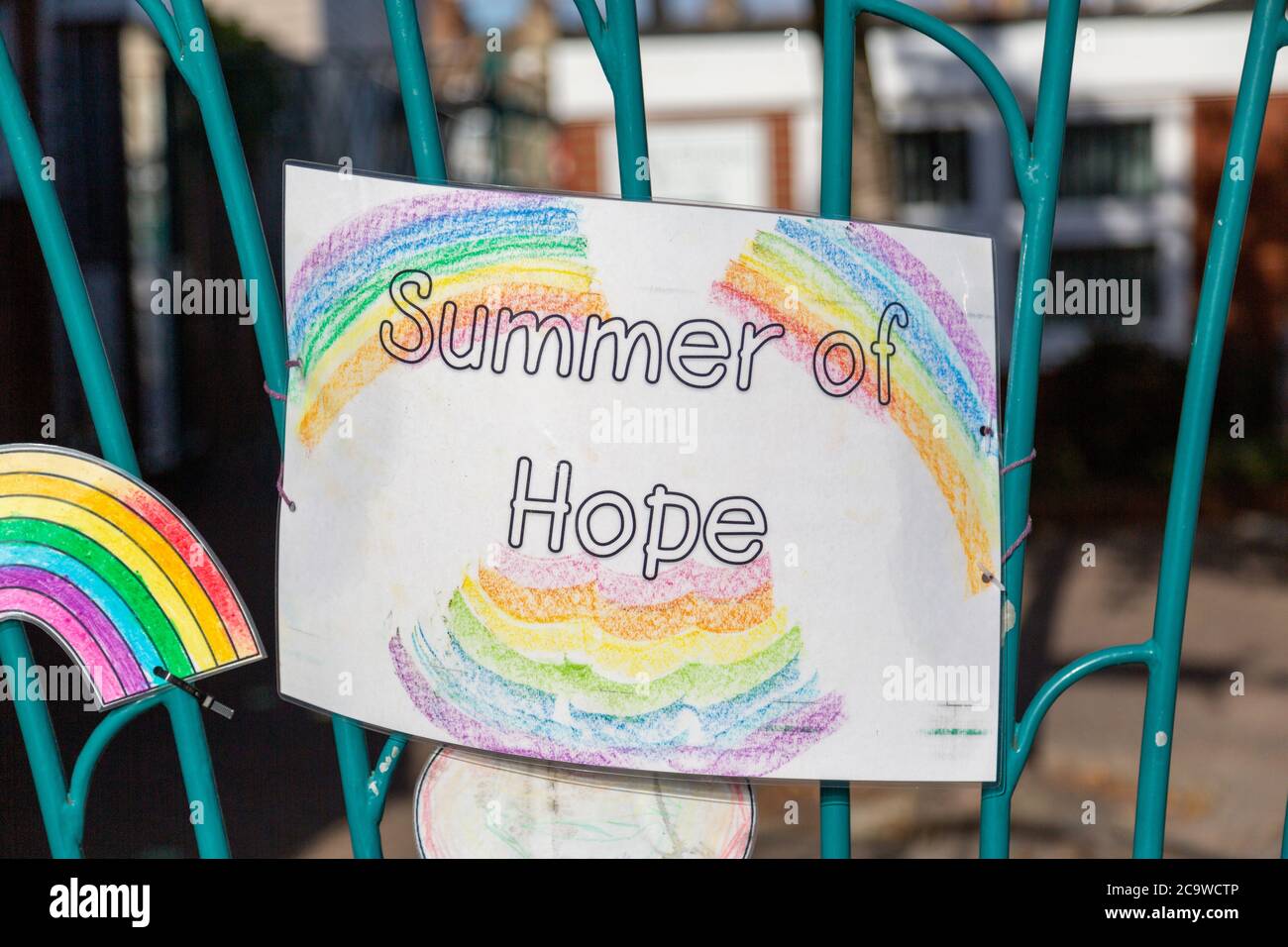 A children's drawing on a school gate with rainbows and summer of hope written on it during the Coronavirus pandemic Stock Photo