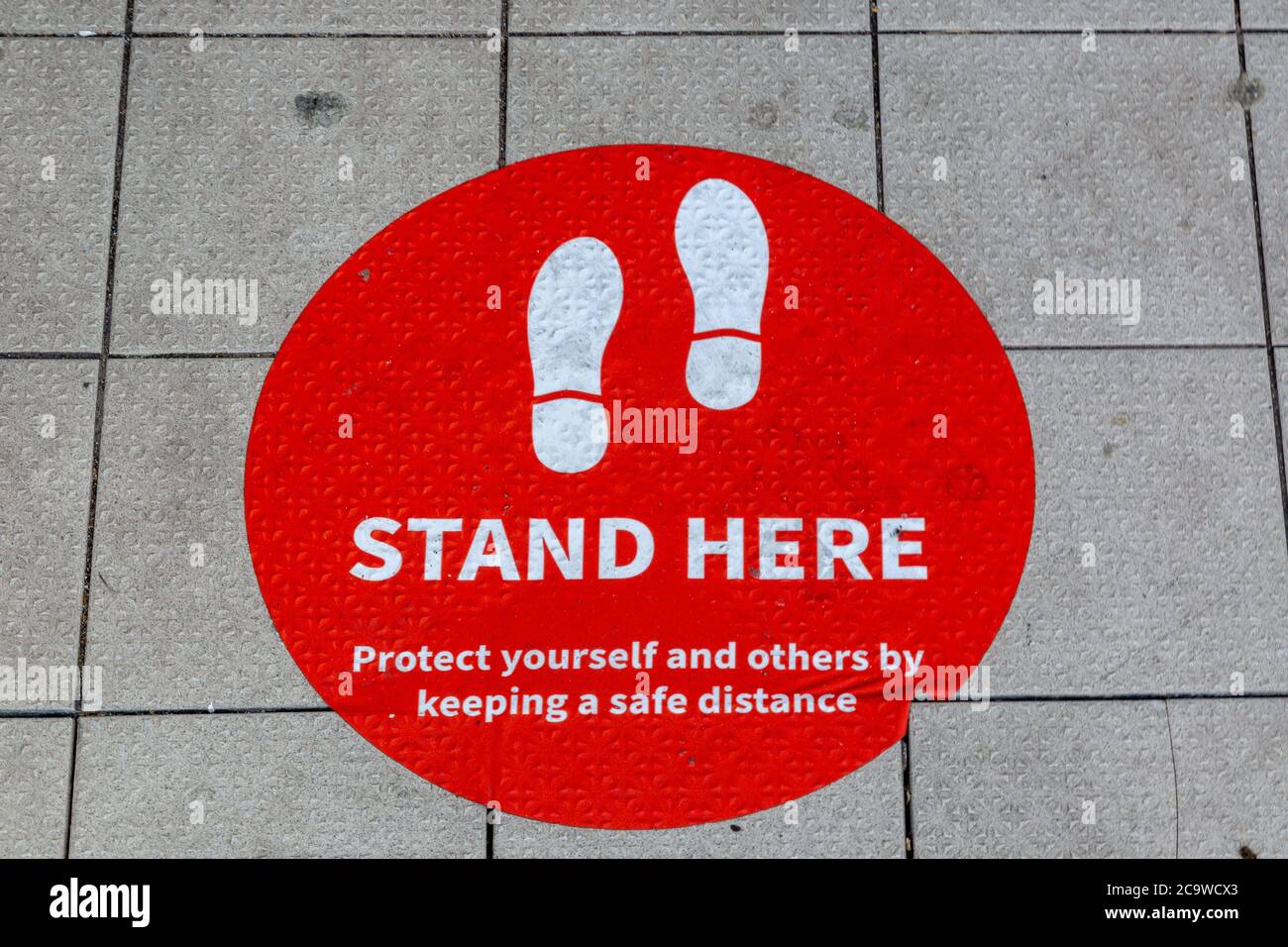 A sign on the ground outside a shop telling customers where to queue so ...