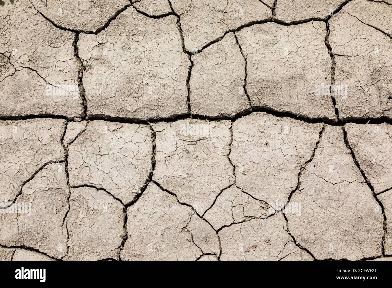 Dry cracked soil. The fields are missing rain. Stock Photo