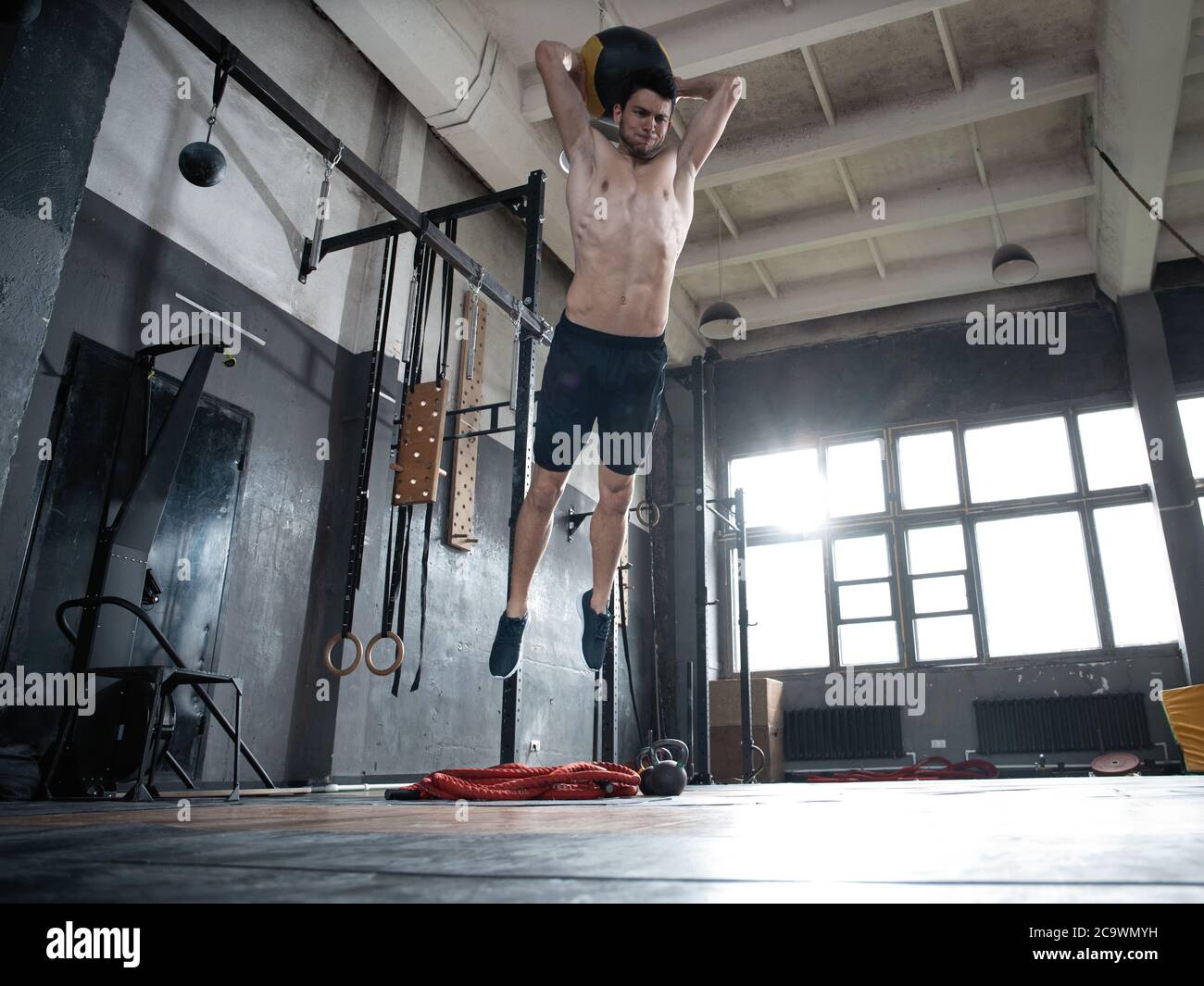 Fit man throwing medicine ball doing ball slam against gym floor or shoulder press upper body