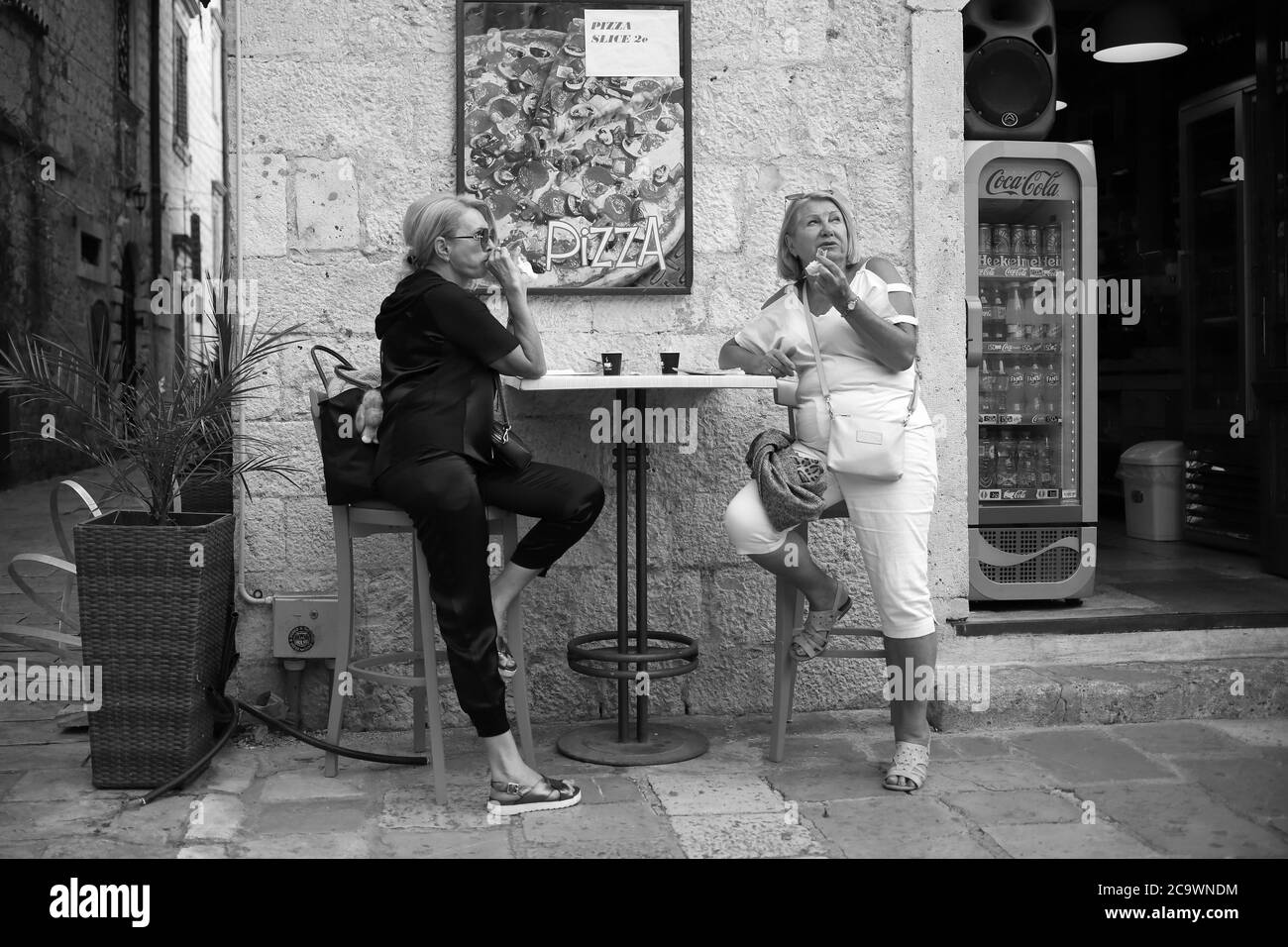 Montenegro, Sep 22, 2019: Street scene with two women having snack and coffee at an outdoor cafe in Kotor Old Town (B/W) Stock Photo