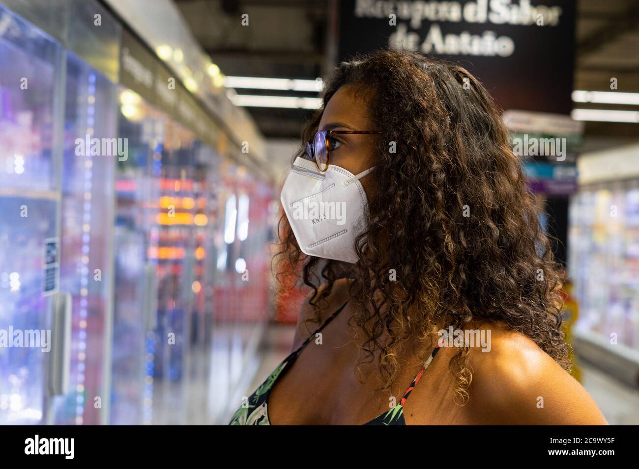 Brazilian young woman shopping in the supermarket with mask. New normality concept. Stock Photo