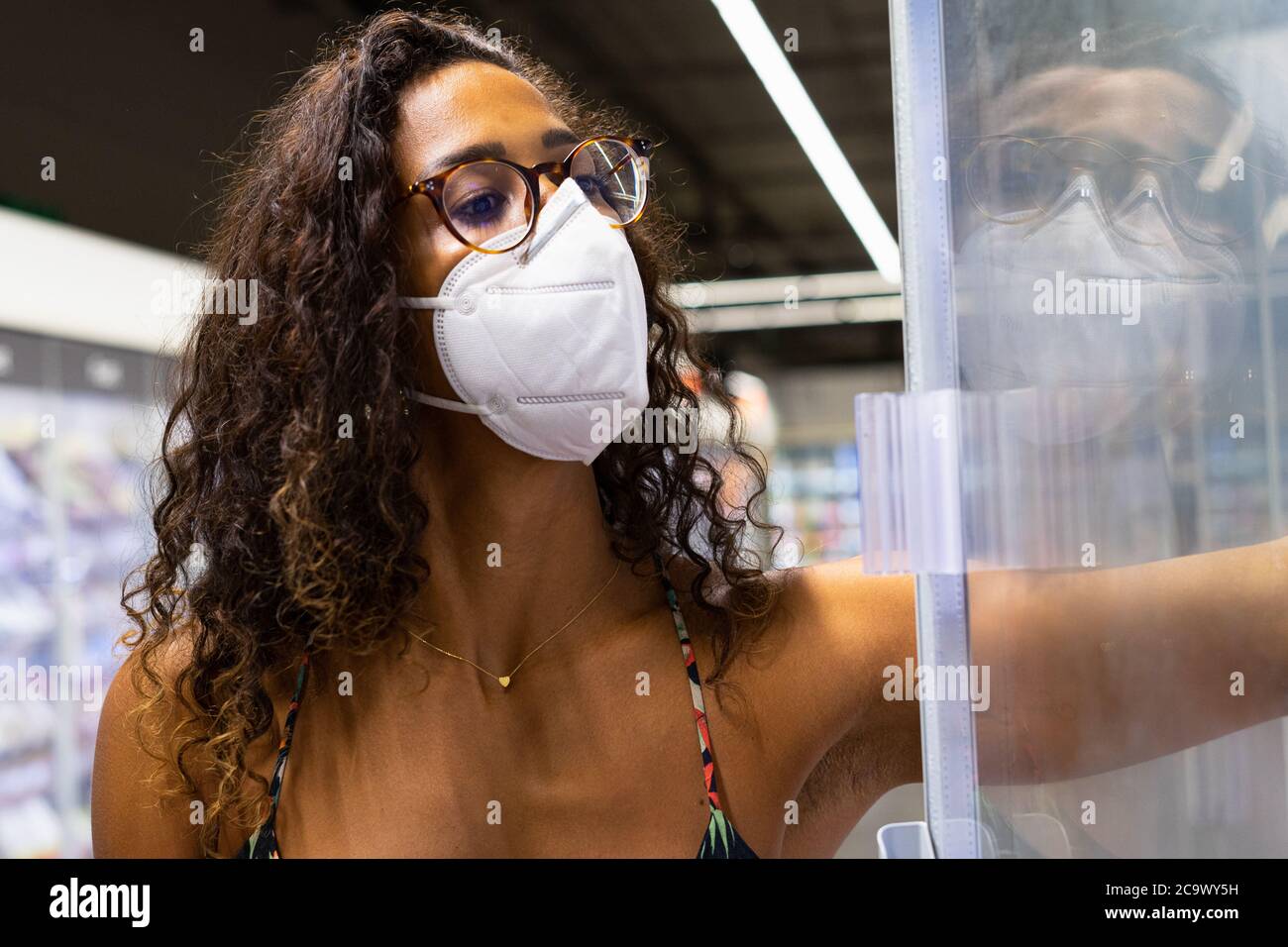 Brazilian young woman shopping in the supermarket with mask. New normality concept. Stock Photo