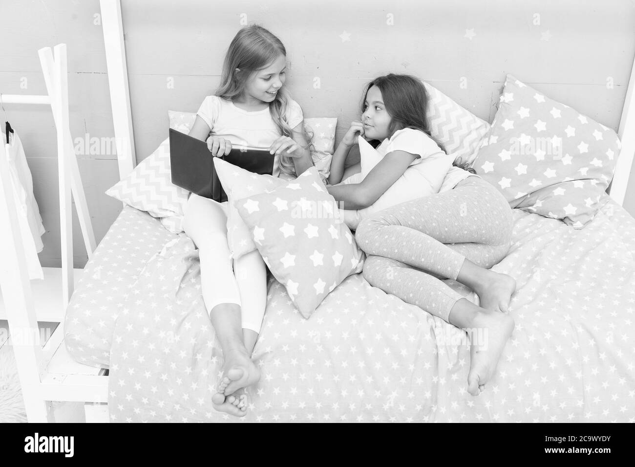 Read to me. Little girl read story to sister. Small kids read before bed. Literature and library. Children development. Developing imagination through reading. Just want nice bedtime read. Stock Photo