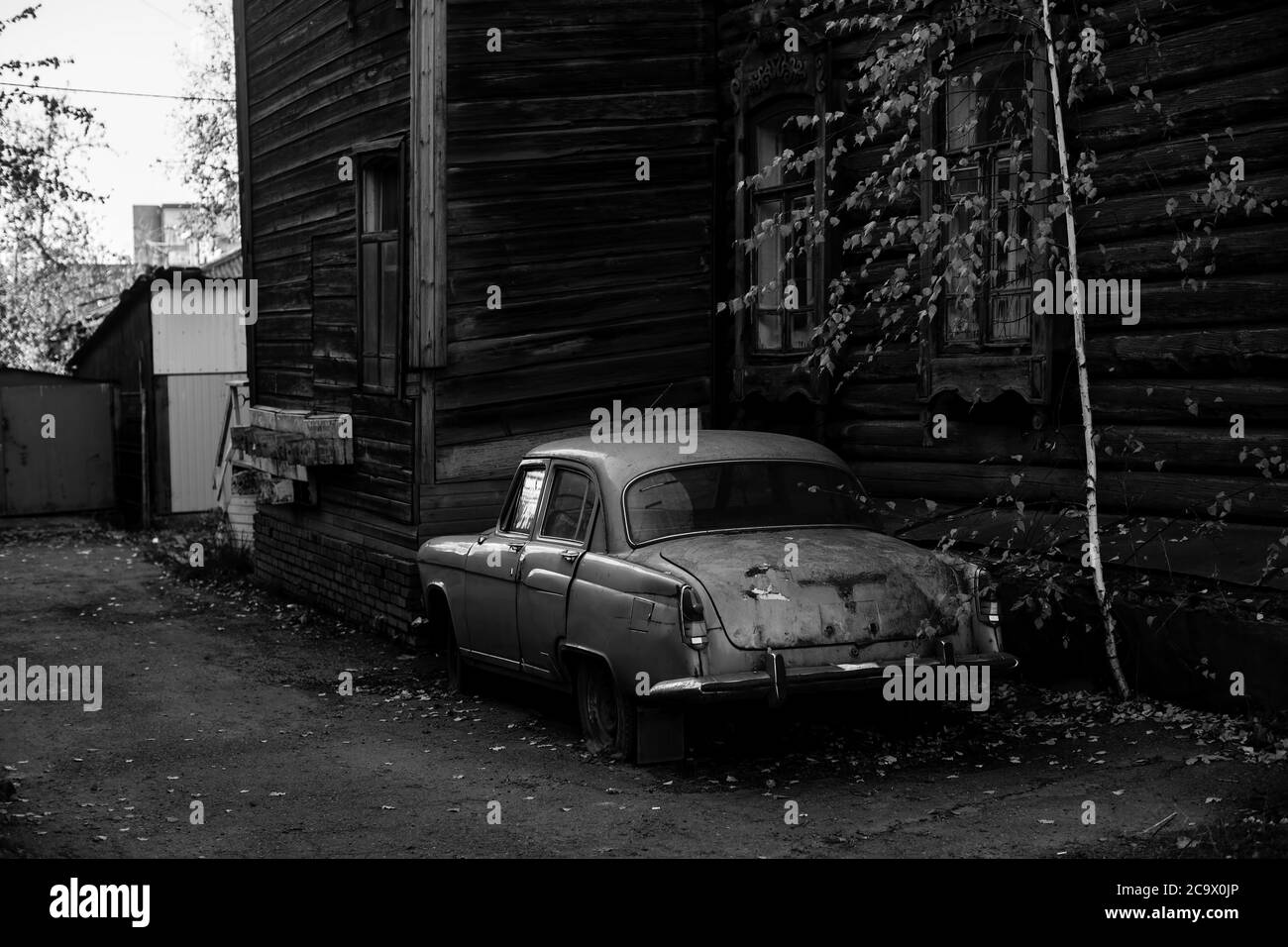 Vintage car near the wooden hause in Tomsk, Siberia. Black and white photo. Stock Photo