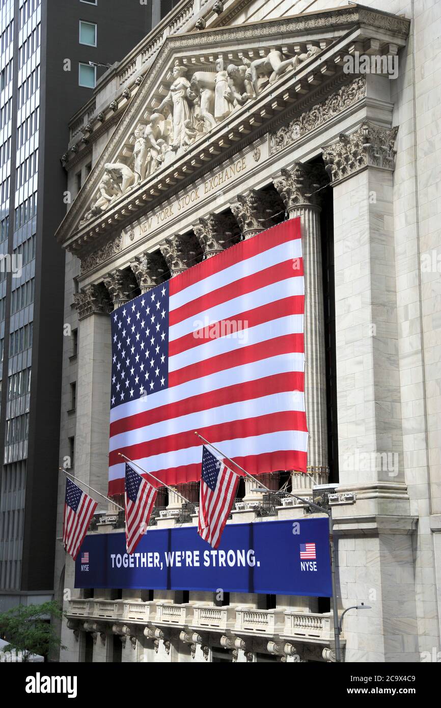 Exterior of the New York Stock Exchange with Together We’re Strong banner hanging during the coronavirus pandemic.  The NYSE partially reopened its trading room floor May 26, which was closed on March 23rd due to the COVID-19 pandemic, the first time operating with it closed in 228 years. Lower Manhattan, Financial District, New York City, USA May 2020 Stock Photo