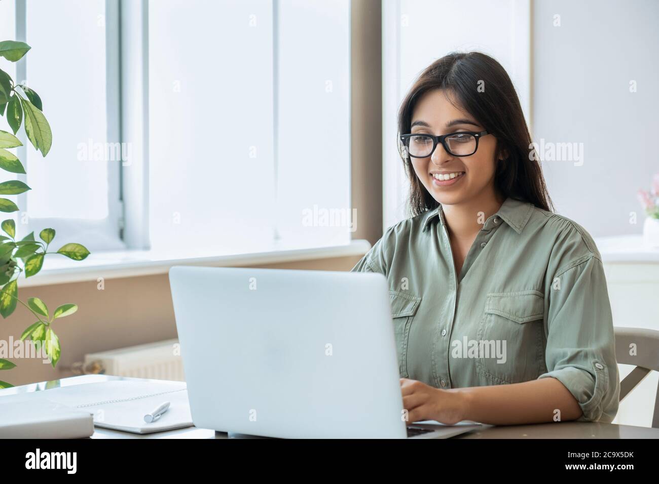Happy indian young woman using laptop computer work study at home office. Stock Photo