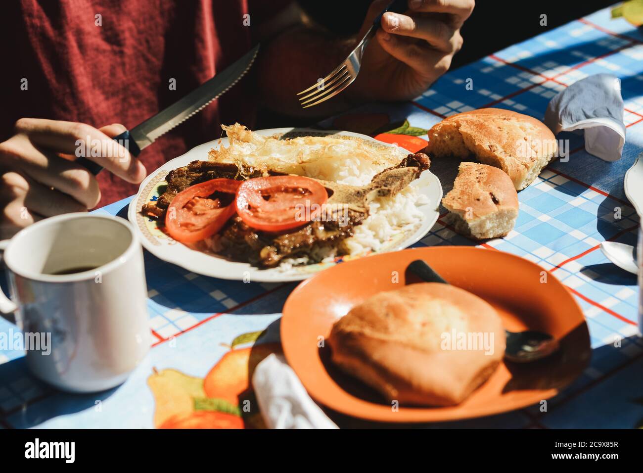 A person has breakfast in a traditional bolivian market from the Yungas region in Bolivia. This food is well known as 'desayuno yungueño' and includes Stock Photo