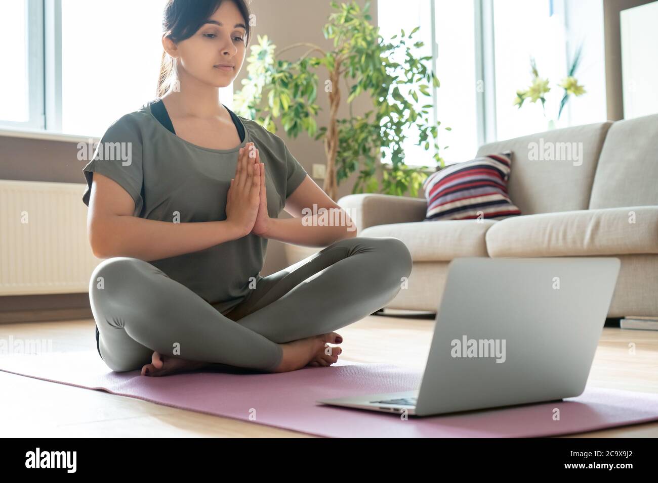 Young mindful indian woman meditate watching online yoga class tutorial at home. Stock Photo