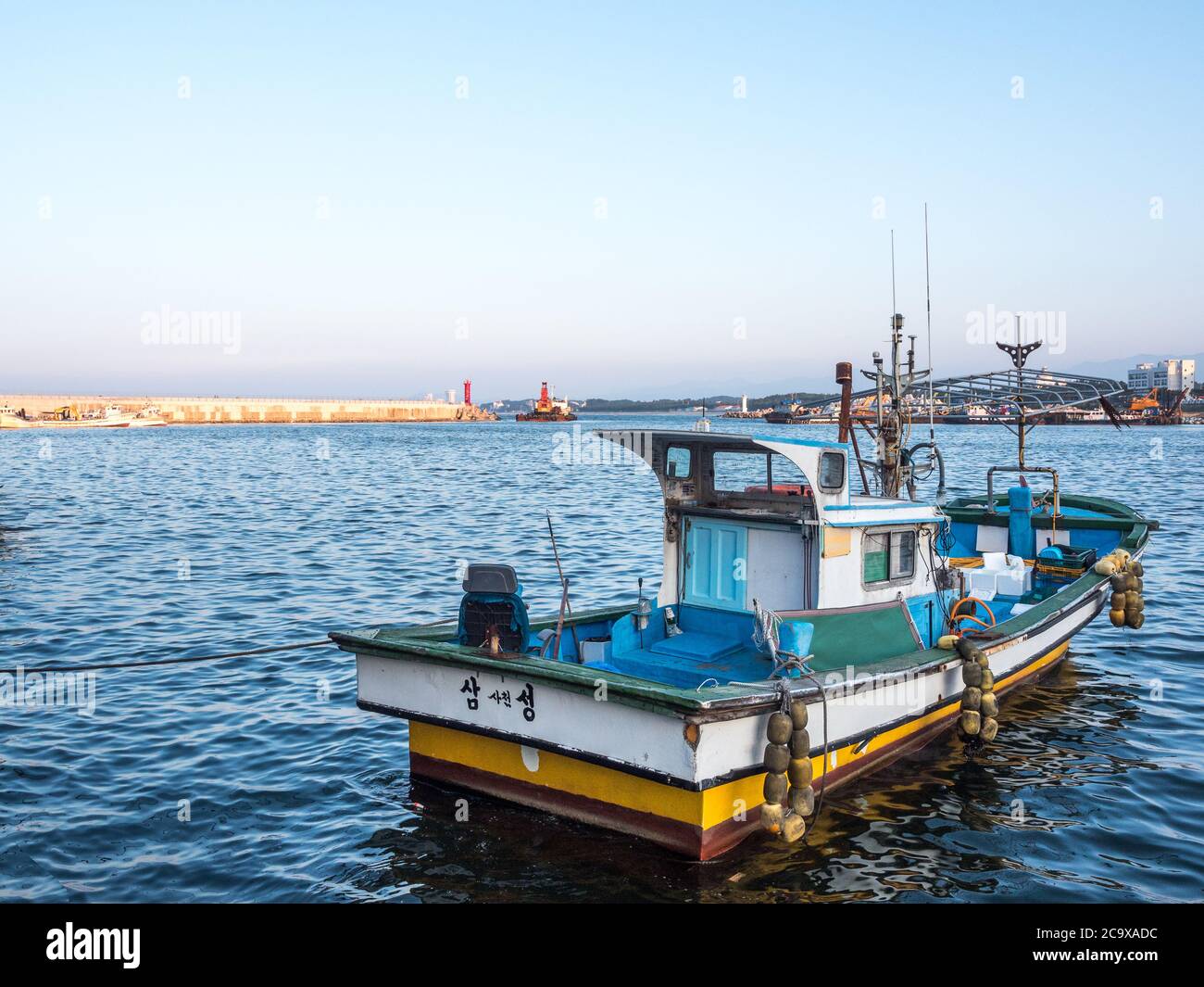 Gangneung, Gangwon province, South Korea - A fishing boat on the Sacheon Harbor in East Coast. Peaceful landscape of blue ocean and sunset sky. Stock Photo