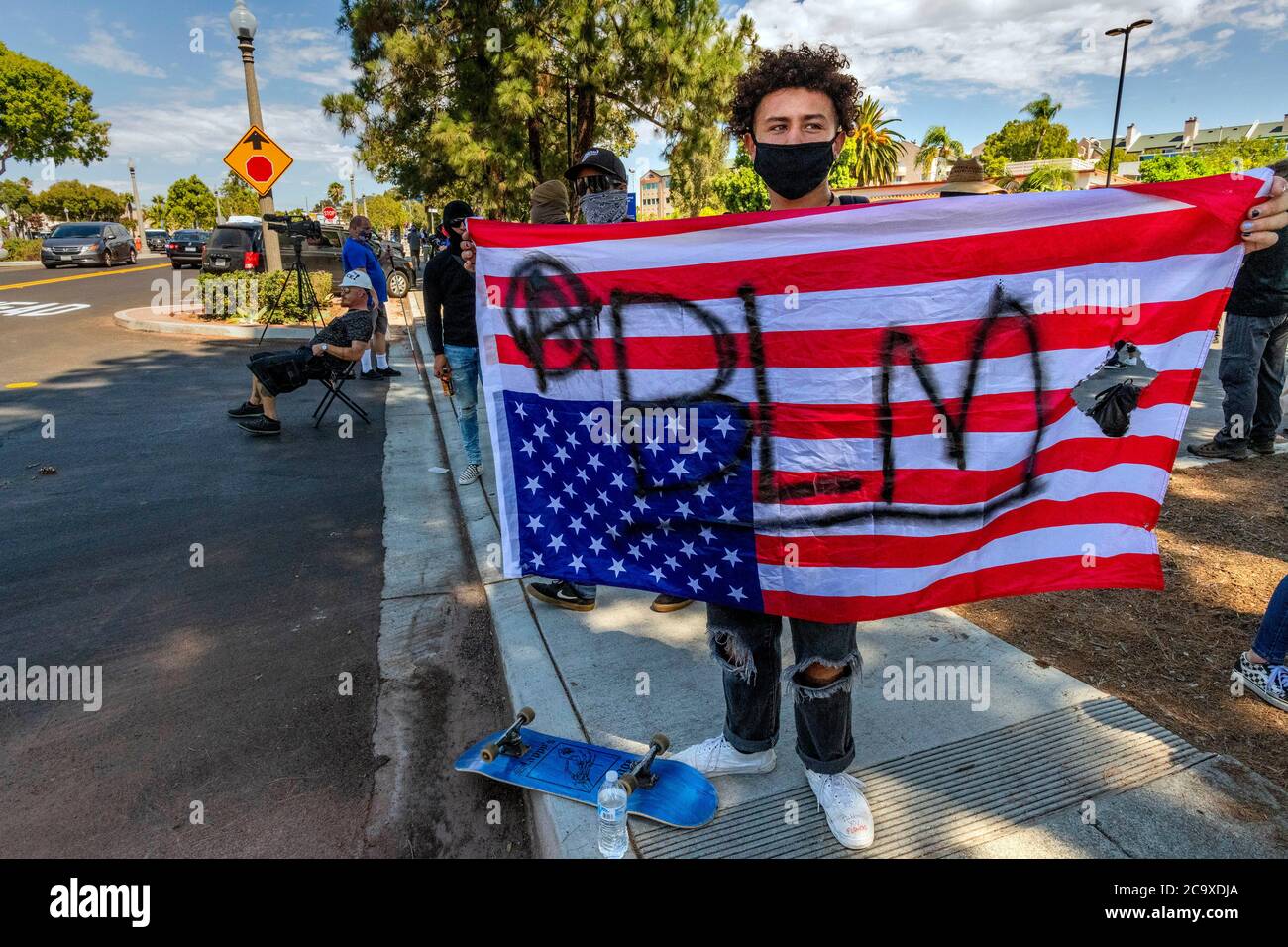 La Mesa, California, USA. 1st Aug, 2020. A participant in a Black Lives Matter Protest in La Mesa, California on August 1, 2020, holds an upside-down US flag. An upside-down flag is a universal sign of distress, and this flag has been marked with Ã¢â‚¬Å“BLMÃ¢â‚¬Â for for the Black Lives Matter movement and an Ã¢â‚¬Å“AÃ¢â‚¬Â in a circle that signifies anarchy. Credit: David Barak/ZUMA Wire/Alamy Live News Stock Photo