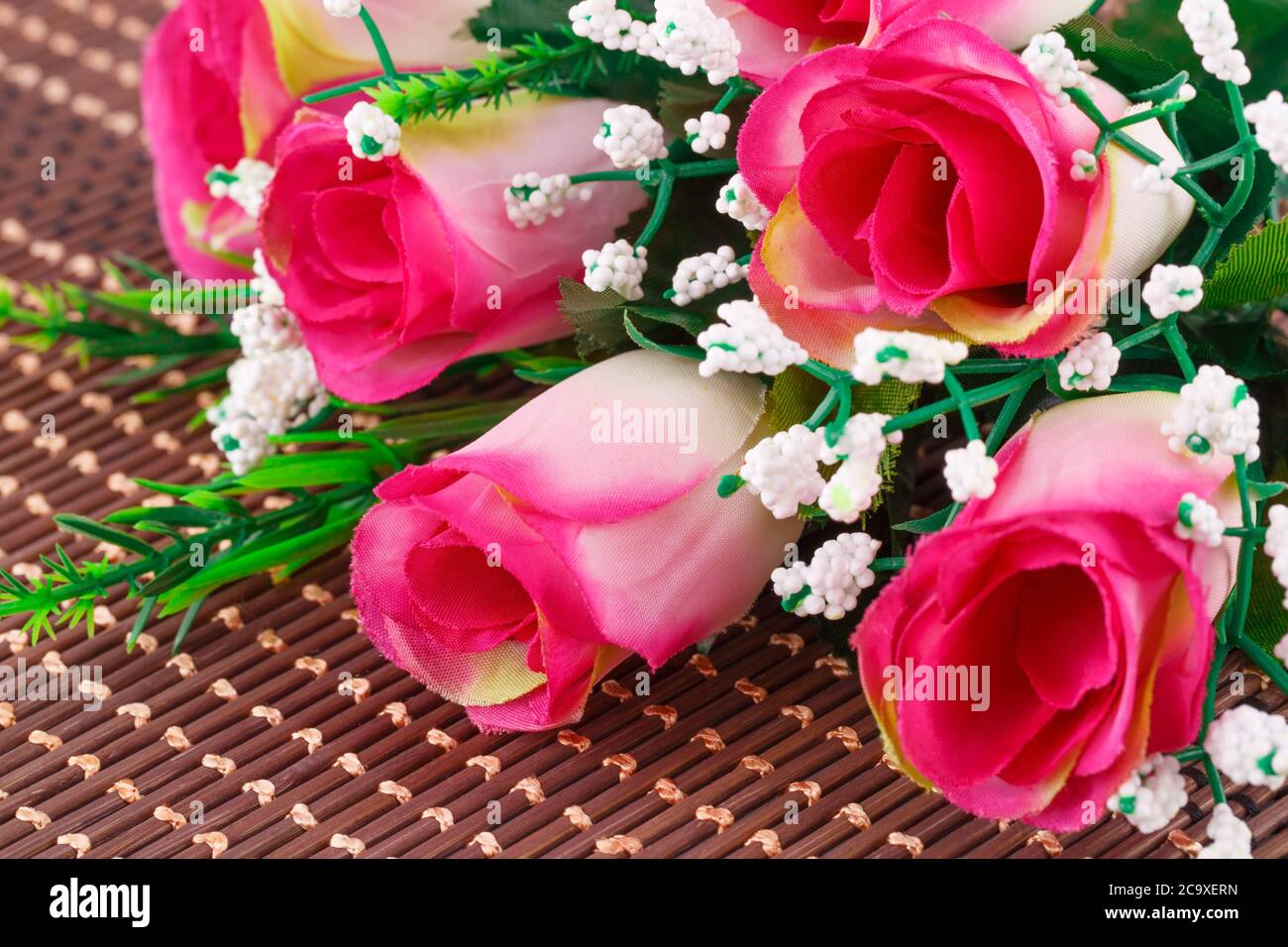 Pink fabric roses on bamboo background, closeup picture. Stock Photo
