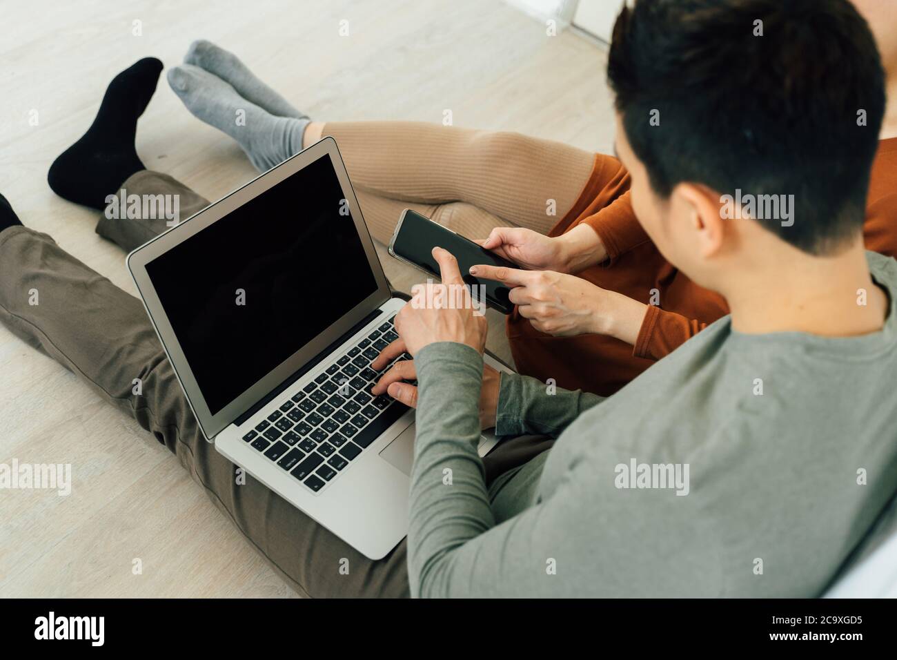 Couple sitting on bed with computer and smartphone high angle view Stock Photo