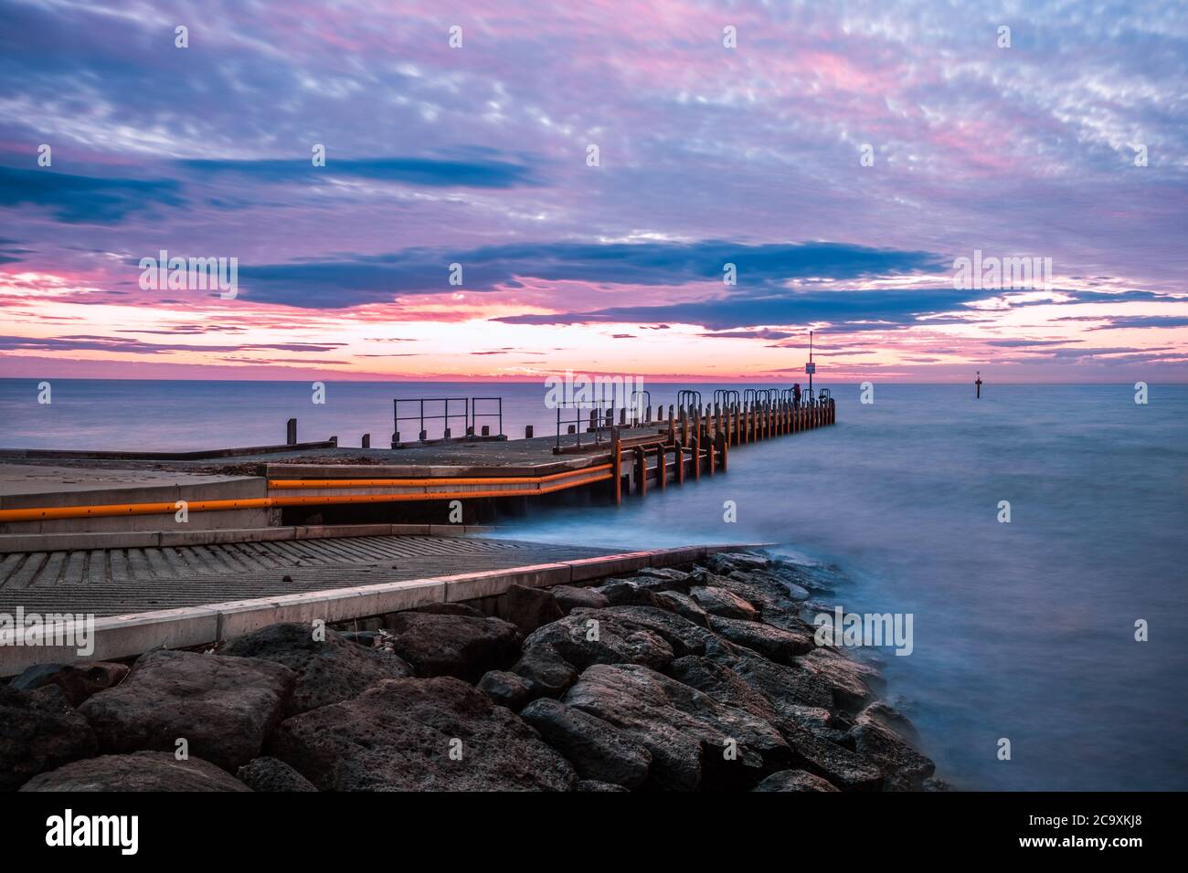 Scenic sunset over ocean and boat jetty - long exposure landscape Stock Photo