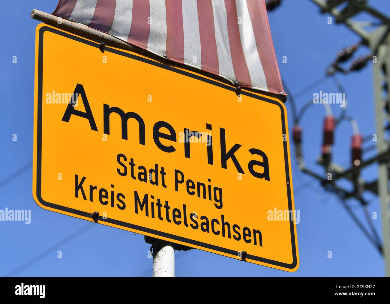Amerika, Germany. 01st Aug, 2020. A place-name sign of America hangs under a flag of the USA in the village in the Mulde Valley. It is not known exactly how the present part of the town of Penig got its name. Credit: Hendrik Schmidt/dpa-Zentralbild/ZB/dpa/Alamy Live News Stock Photo