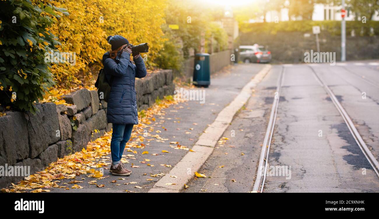 Woman tourist photographing autumn city street Stock Photo