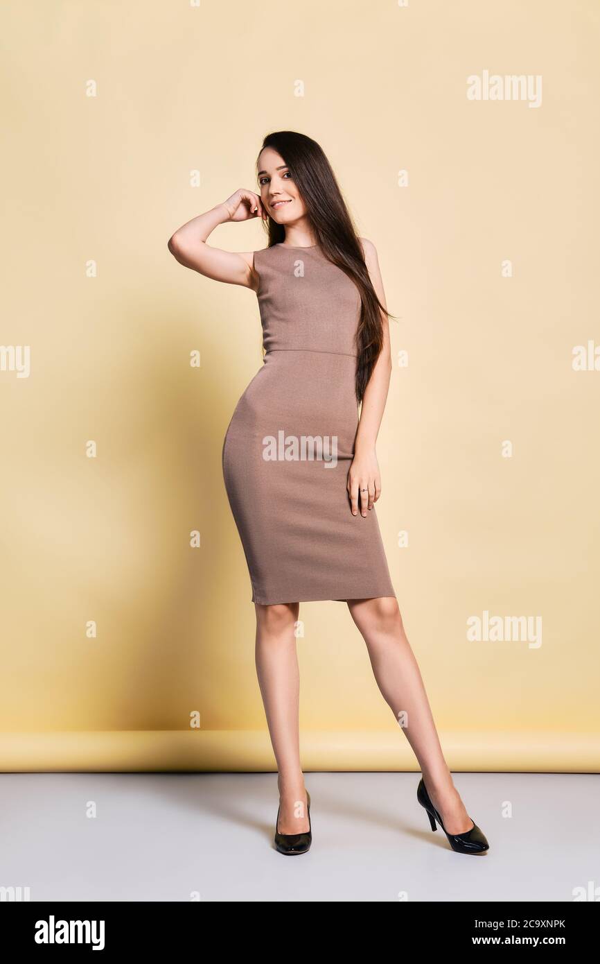 Lovely young woman in tight knitted dress, long straight black hair and high heel shoes posing in studio Stock Photo