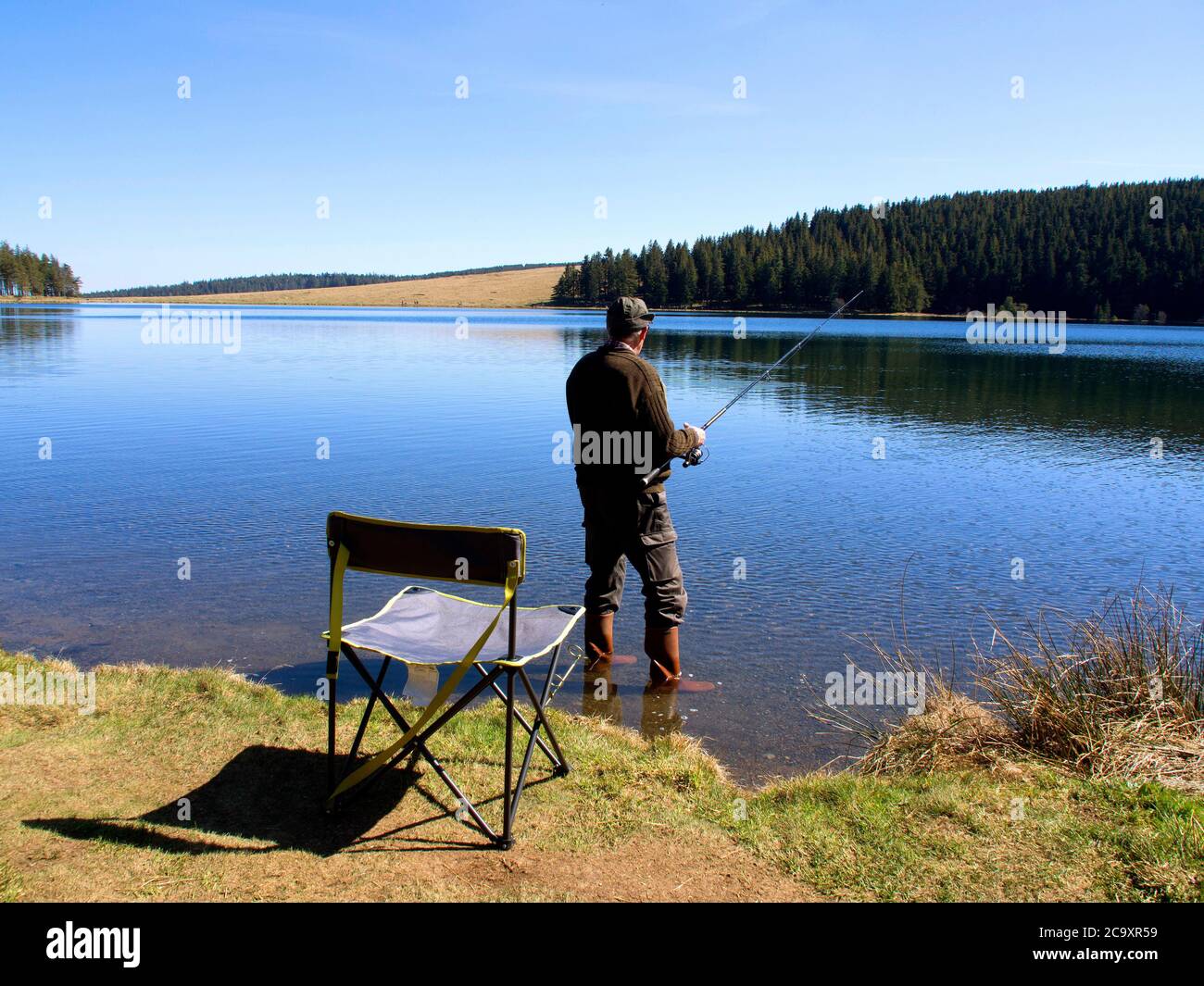 Fisherman fishing in  lake Servieres , Puy de Dome, Auvergne-Rhone-Alpes, France Stock Photo