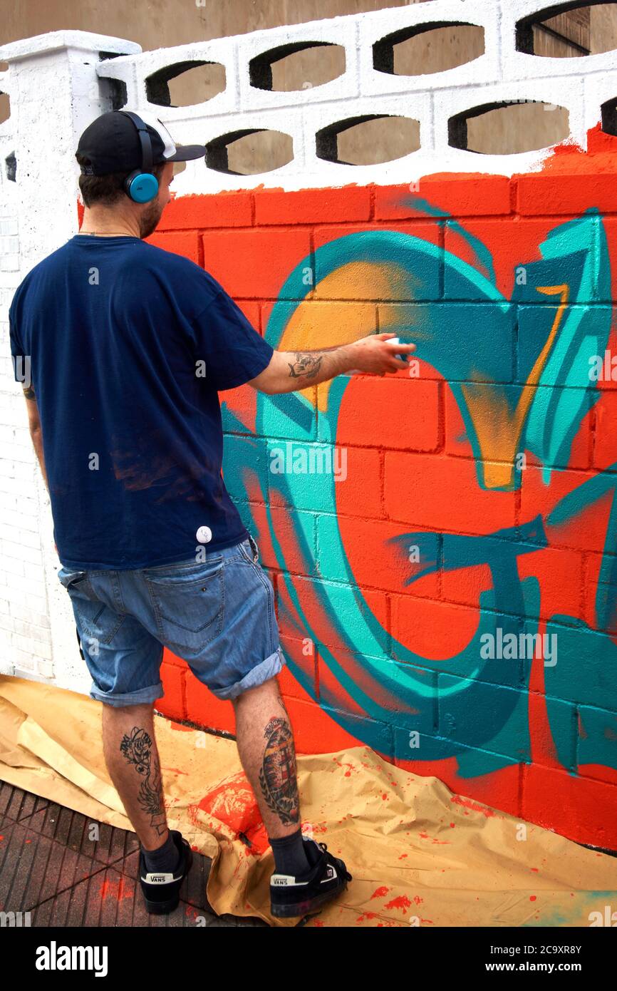 Street artist painting a colorful graffiti on a white wall Stock Photo ...