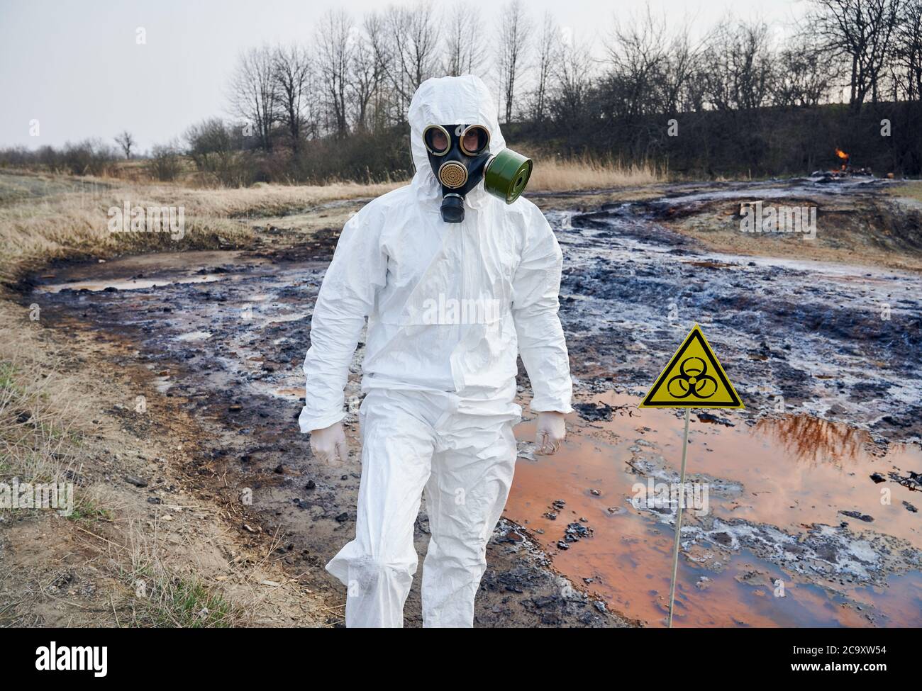 Scientist wearing white protective coverall and gas mask standing next ...