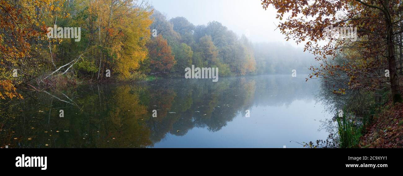 Panorama of colorful autumn trees reflecting in the still river water ...
