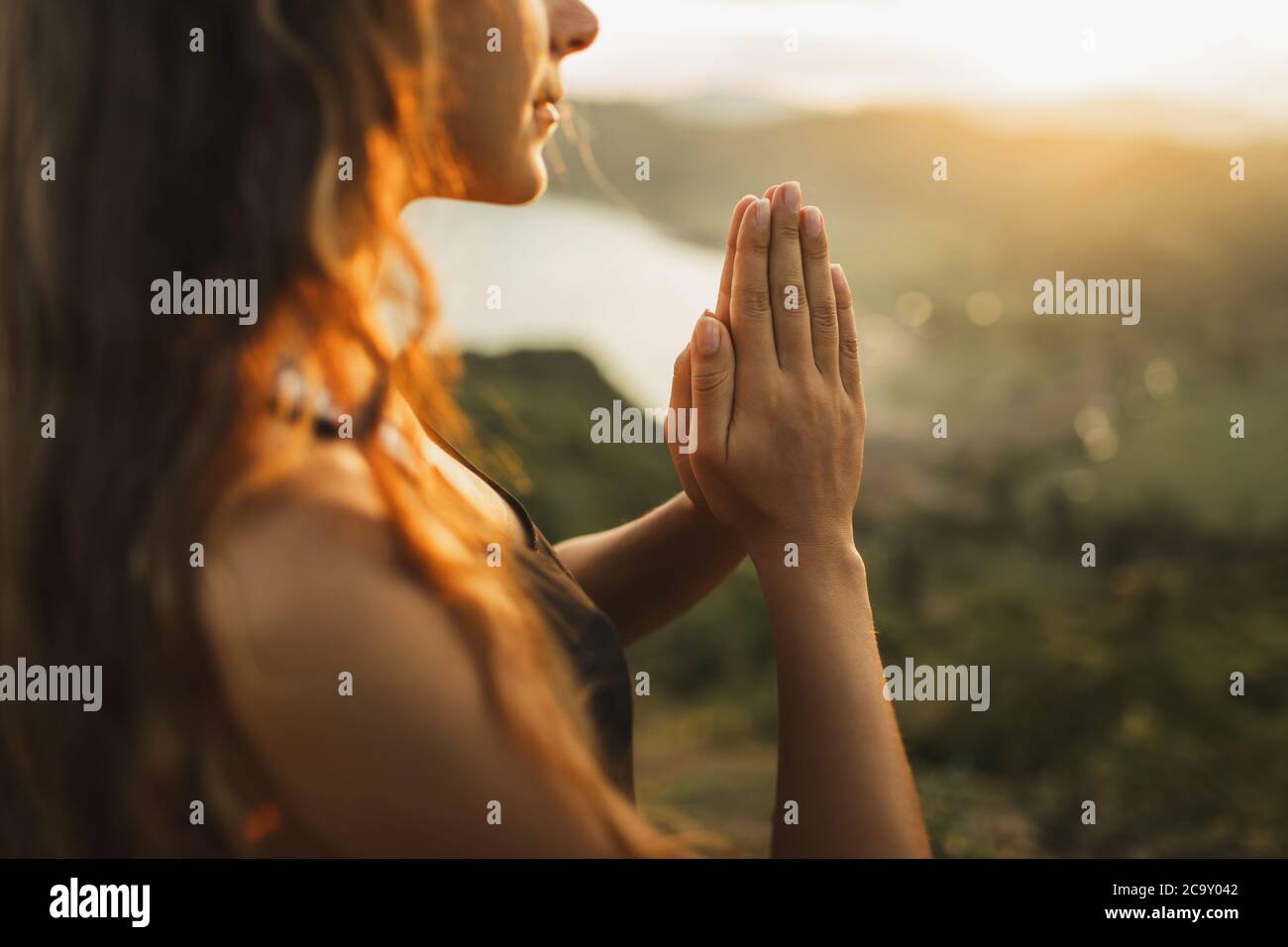 Woman praying alone at sunrise. Nature background. Spiritual and emotional concept. Sensitivity to nature Stock Photo