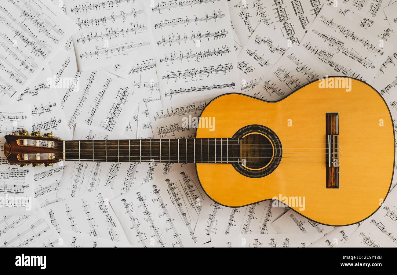 old classical guitar lying on sheet music Stock Photo