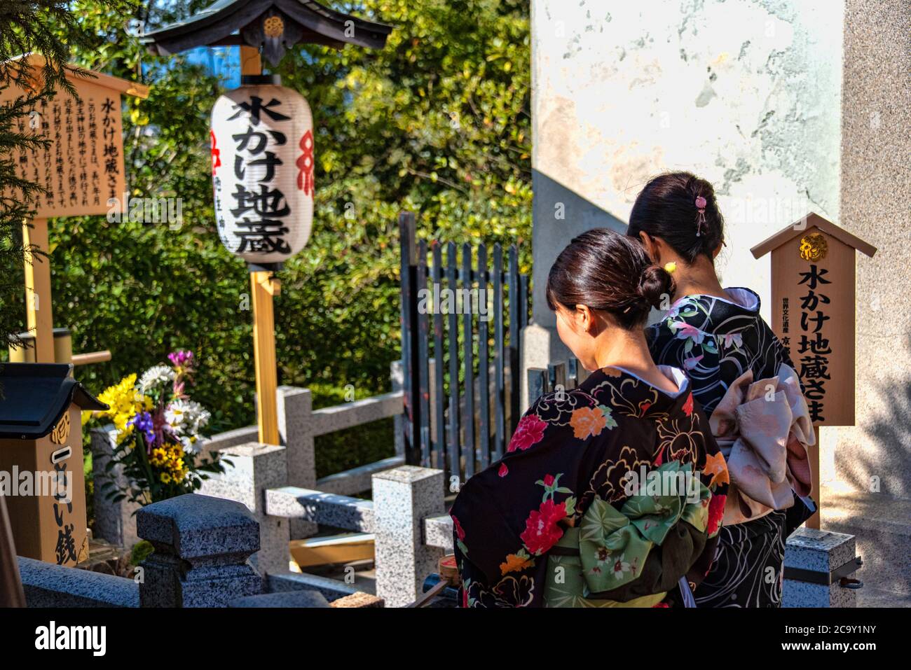 Two yong women praying at temple deities statues, Kiyomizu-dera temple, Kyoto, Japan Stock Photo