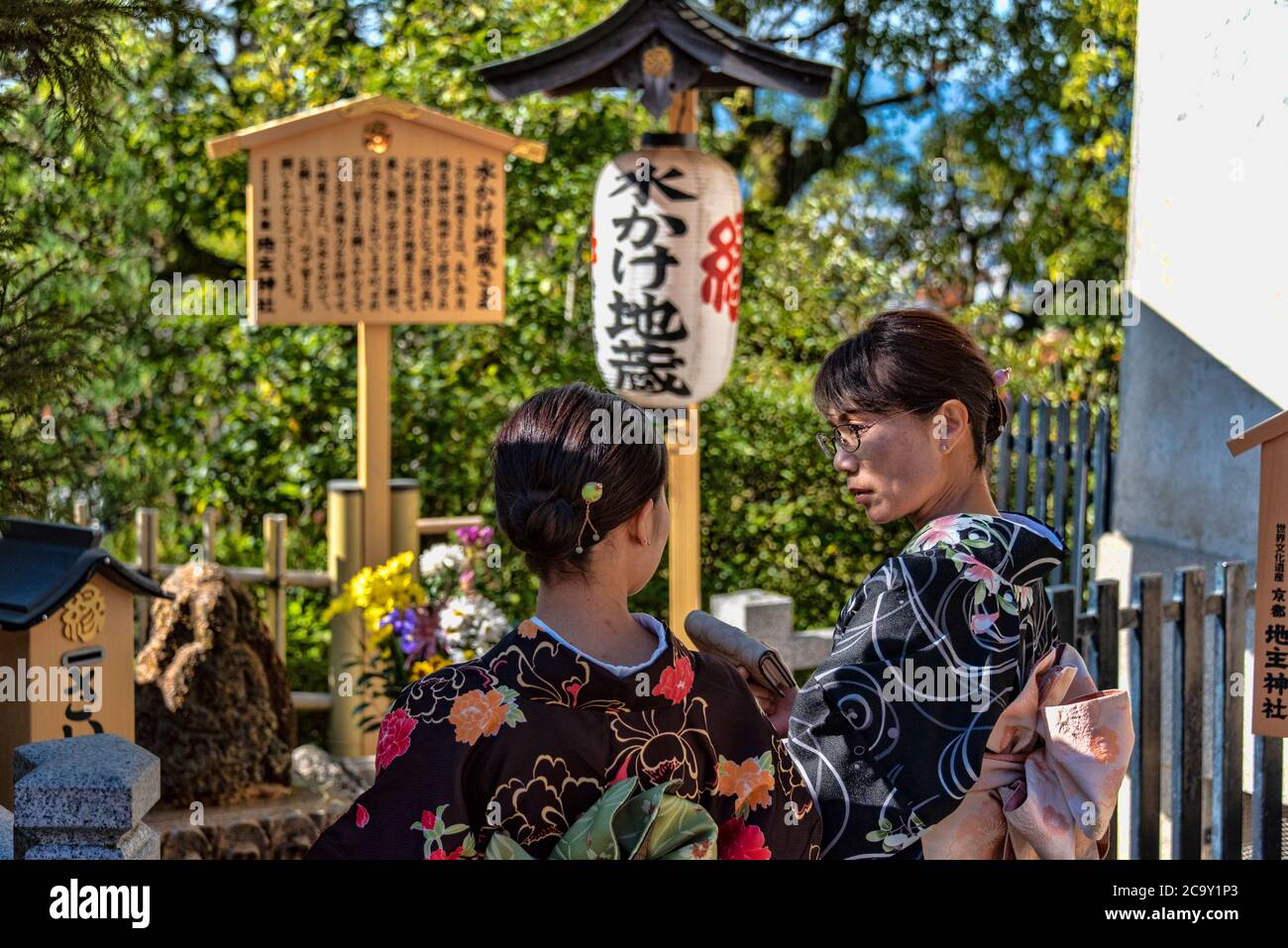 Two yong women praying at temple deities statues, Kiyomizu-dera temple, Kyoto, Japan Stock Photo