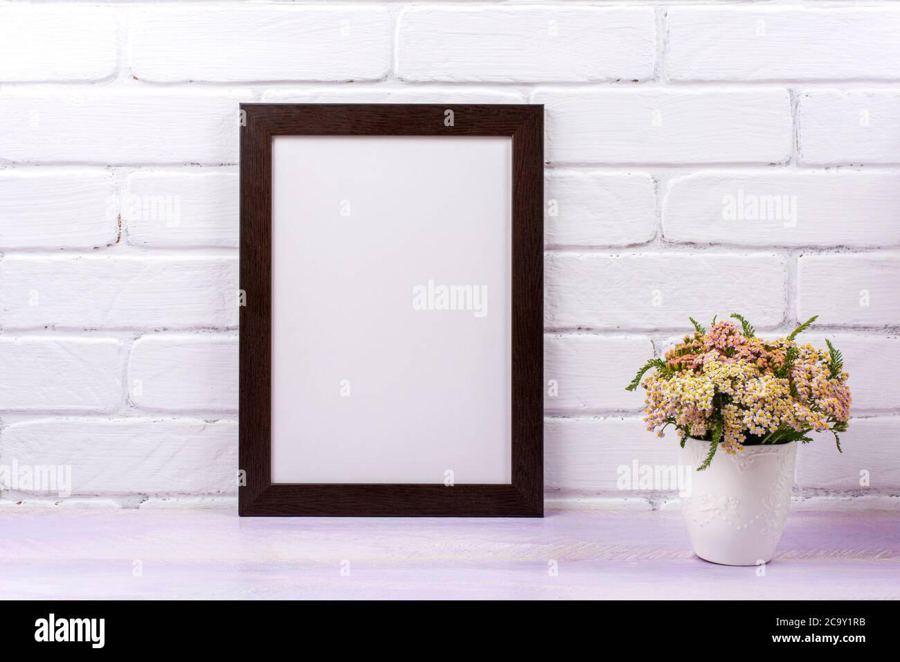 Black brown  frame mockup with pink yarrow in the decorated vase. Empty frame mock up for presentation design. Template framing for modern art. Stock Photo