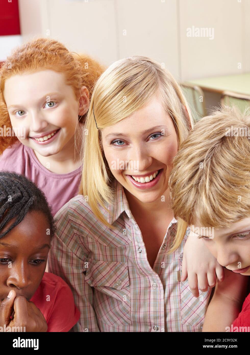 Teacher laughs with her students in class at primary school Stock Photo