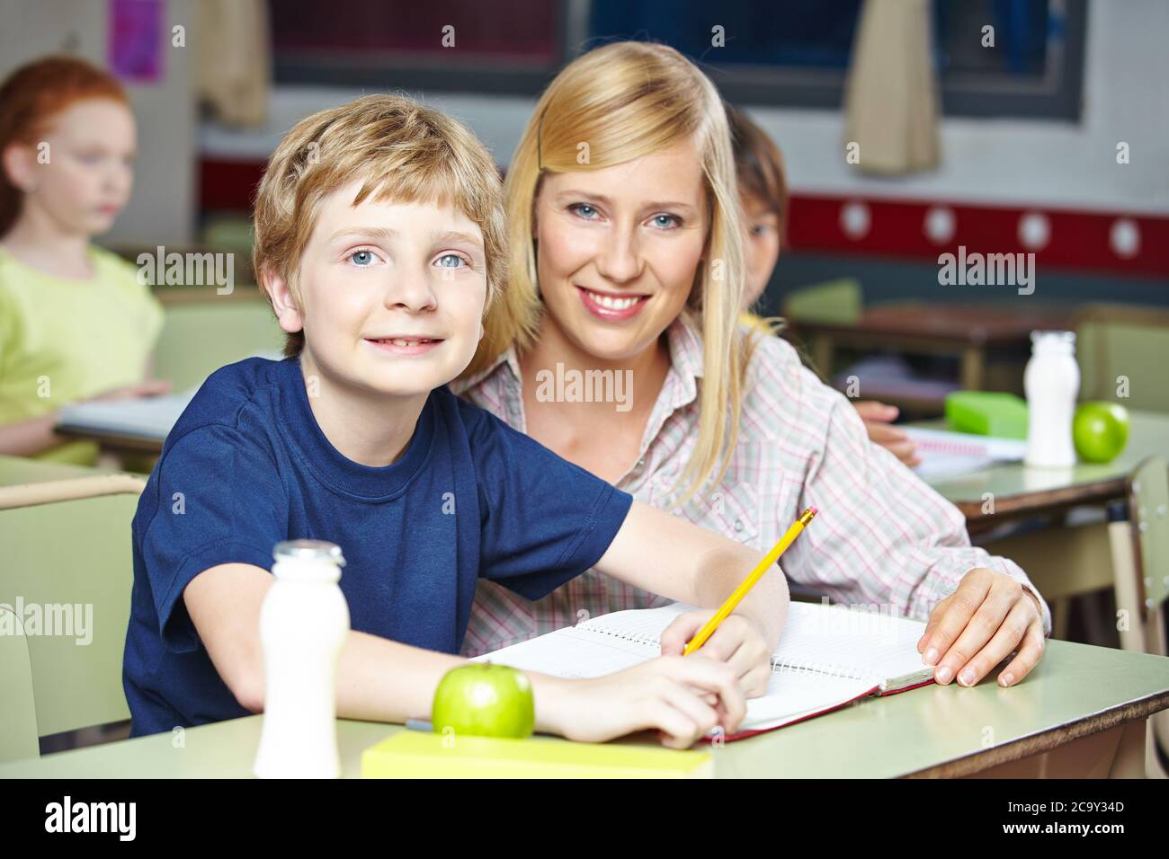 Smiling teacher with student in class at primary school Stock Photo
