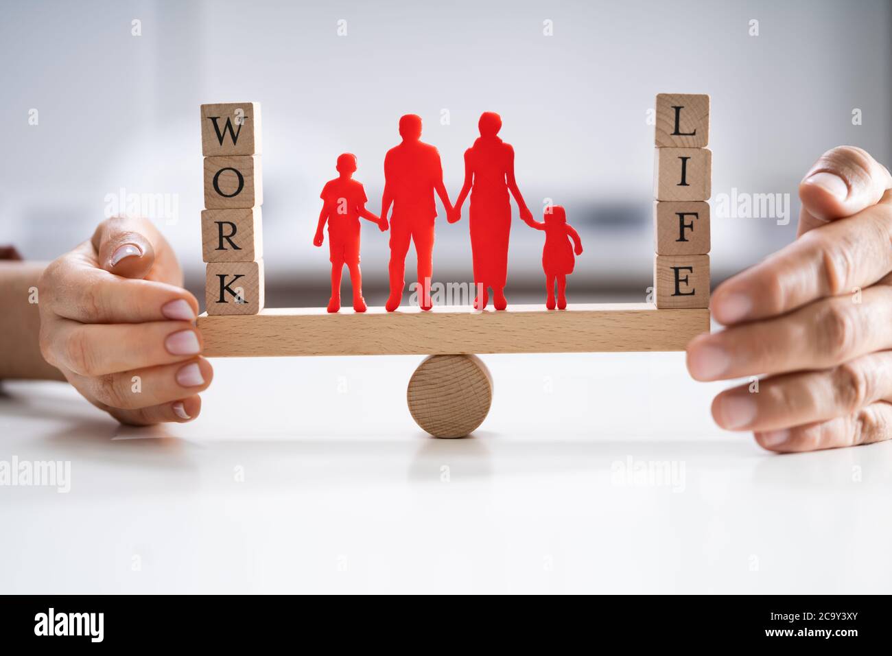 Happy Couple Protecting Balance Between Work And Life With Family Paper Cut Out On Seesaw Stock Photo
