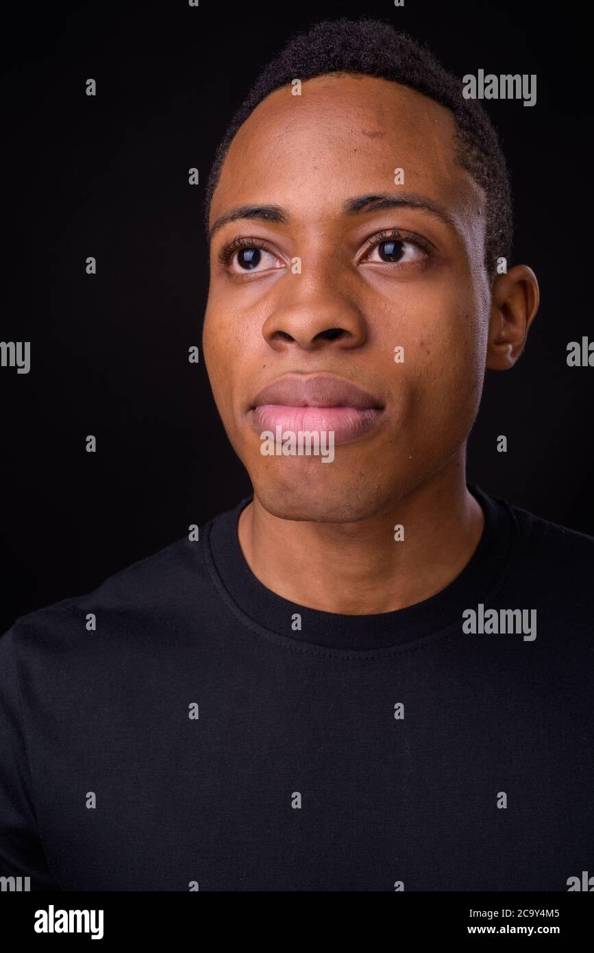 Young handsome African man against black background Stock Photo - Alamy