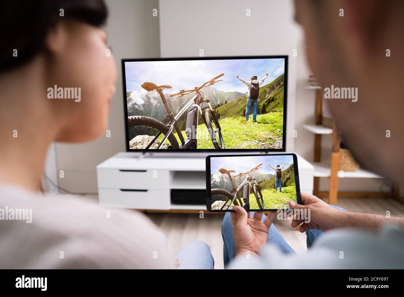 Family Watching TV Through Tablet Television And Movie Streaming Stock Photo