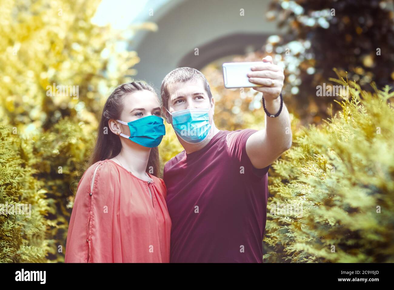 Young people with protective face masks taking selfie in city Stock Photo