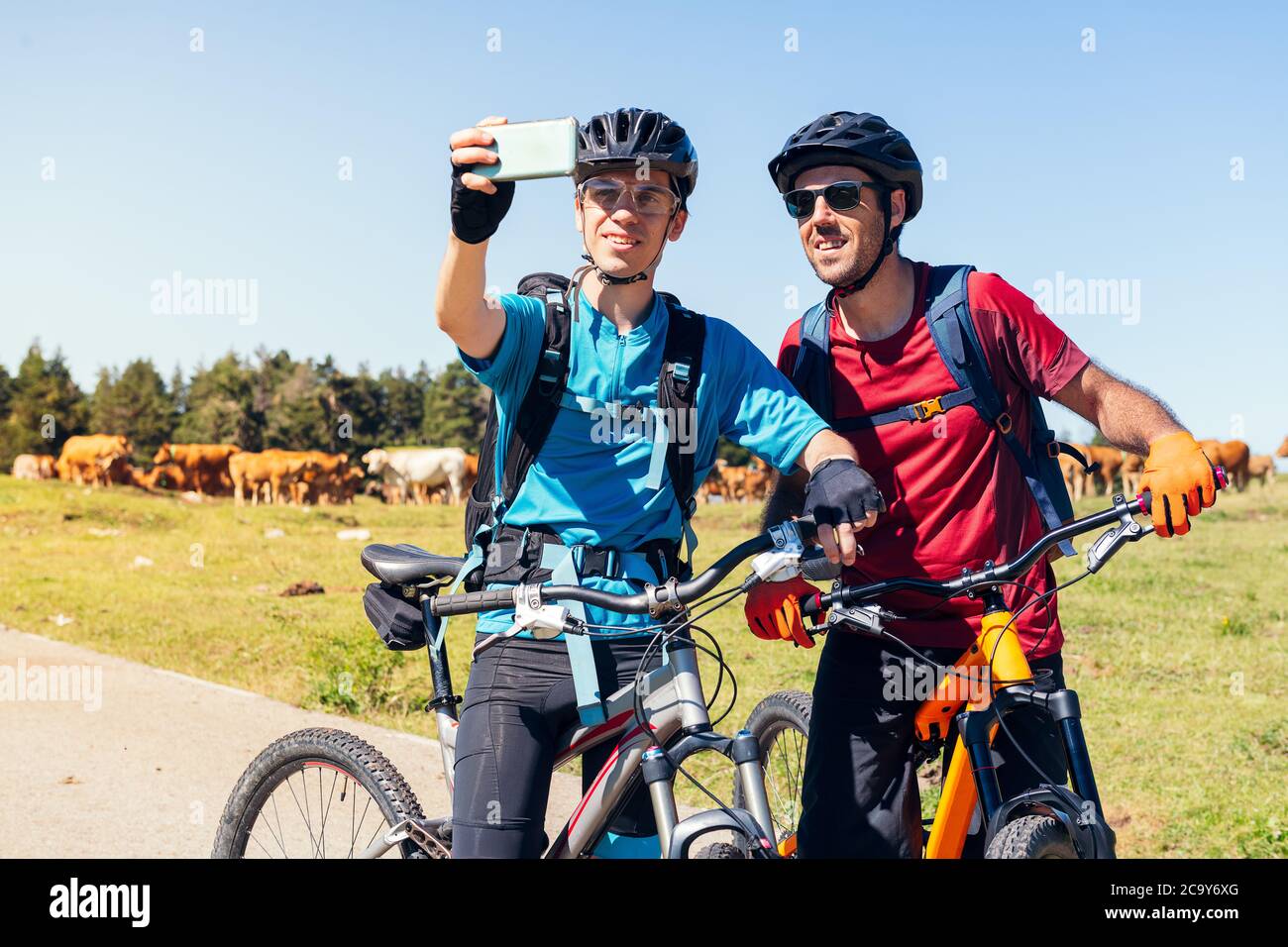 two young cyclists taking a selfie with the phone during their mountain bike route, concept of sport with friends and healthy lifestyle in nature, cop Stock Photo