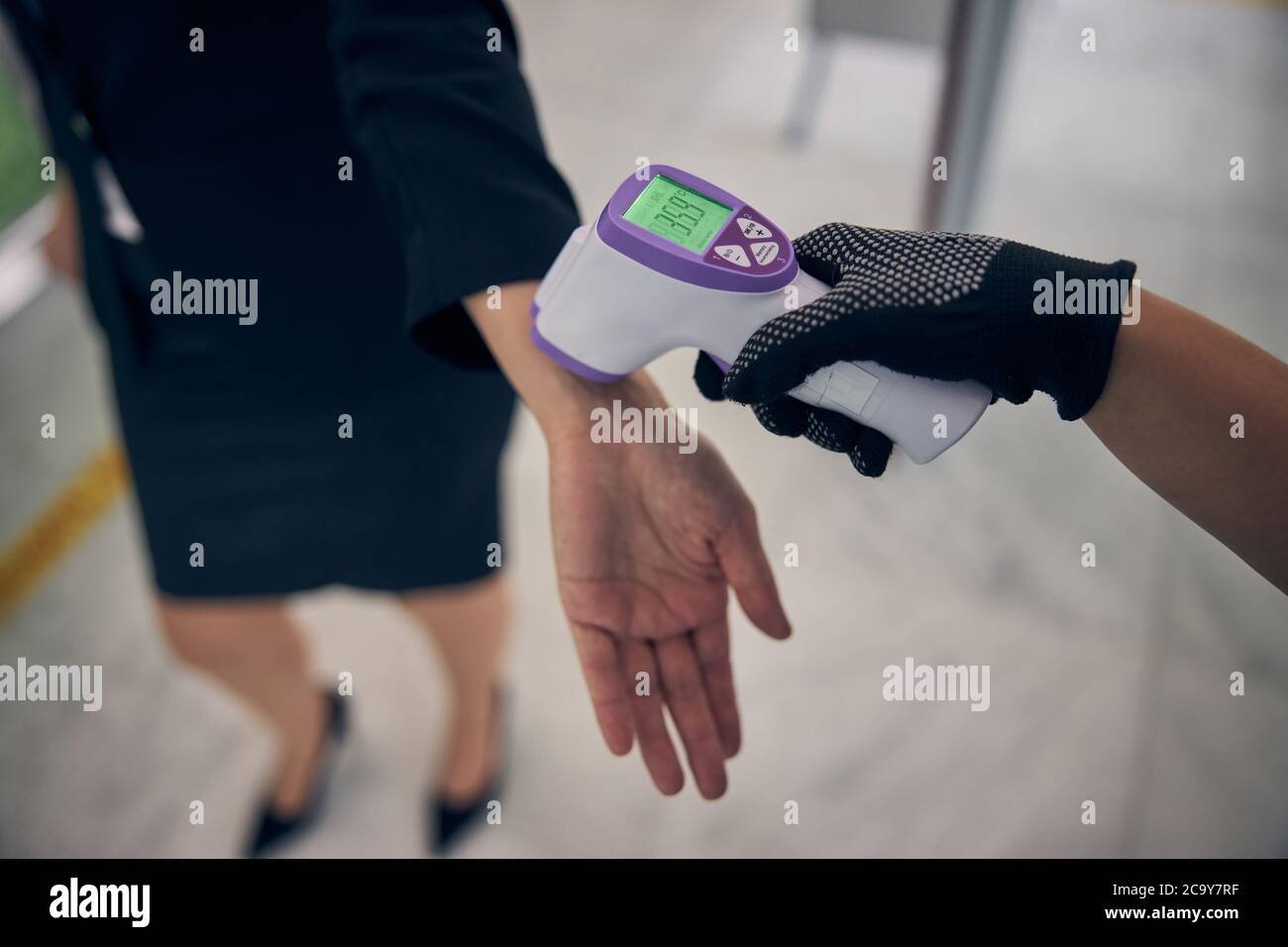 Airport worker checking body temperature of female traveler Stock Photo