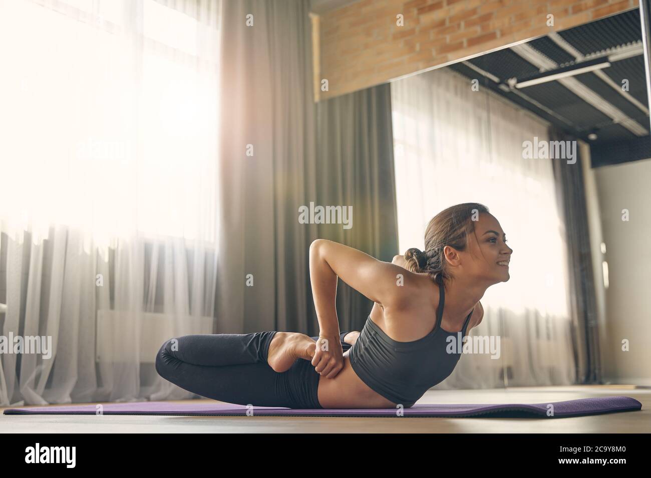 Smiling young woman practicing yoga in studio Stock Photo