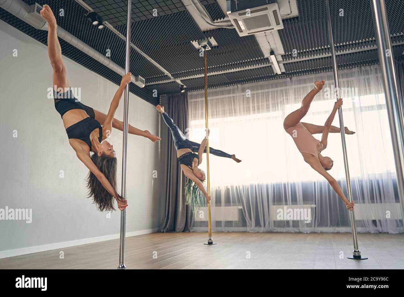 Group of beautiful young women performing pole dance tricks Stock Photo