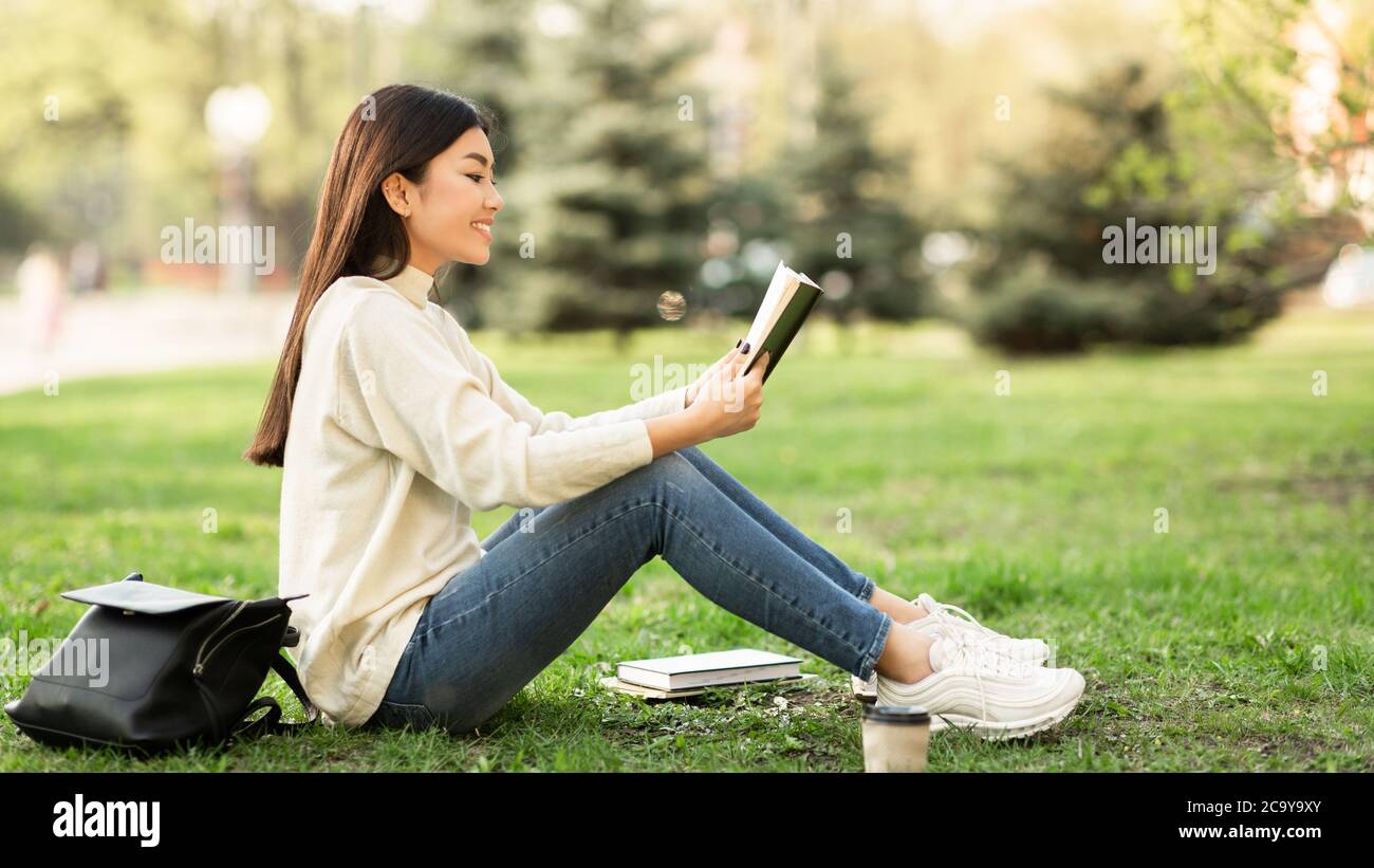 Girl reading a book sitting in the park Stock Photo - Alamy