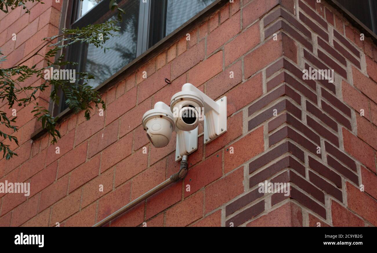 surveillance camera installed on the external brick wall of a residential building for security Stock Photo