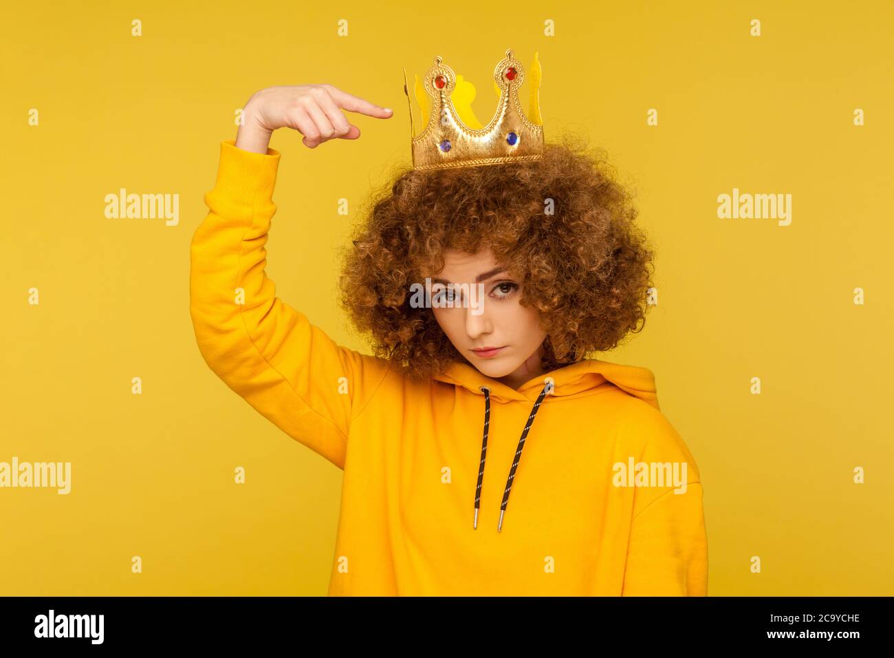 Look, I am best! Selfish haughty curly-haired woman pointing at crown on head and looking with arrogance supercilious, being egoistic with over-inflat Stock Photo