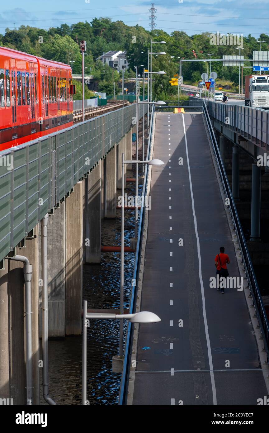 Helsinki / Finland - July 30, 2020: Carbon neutral city life: Bicycle boulevard and a subway track connecting two city boroughs Stock Photo
