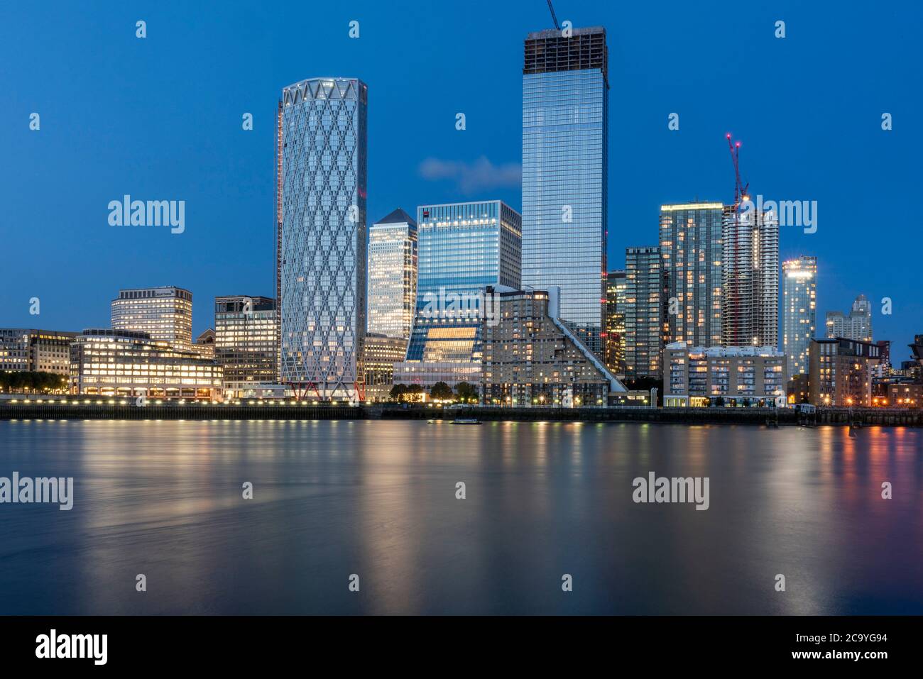 View across Thames from west at sunset with reflection in water. Isle of Dogs, London, United Kingdom. Architect: Various, 2020. Stock Photo