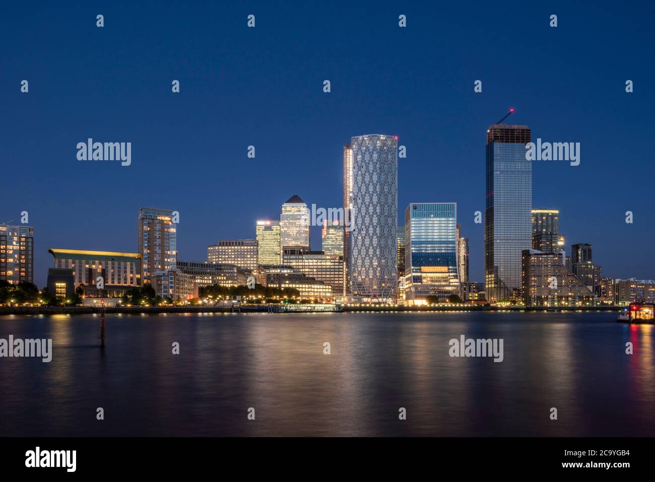 View across Thames from west at sunset with reflection in water. Isle of Dogs, London, United Kingdom. Architect: Various, 2020. Stock Photo
