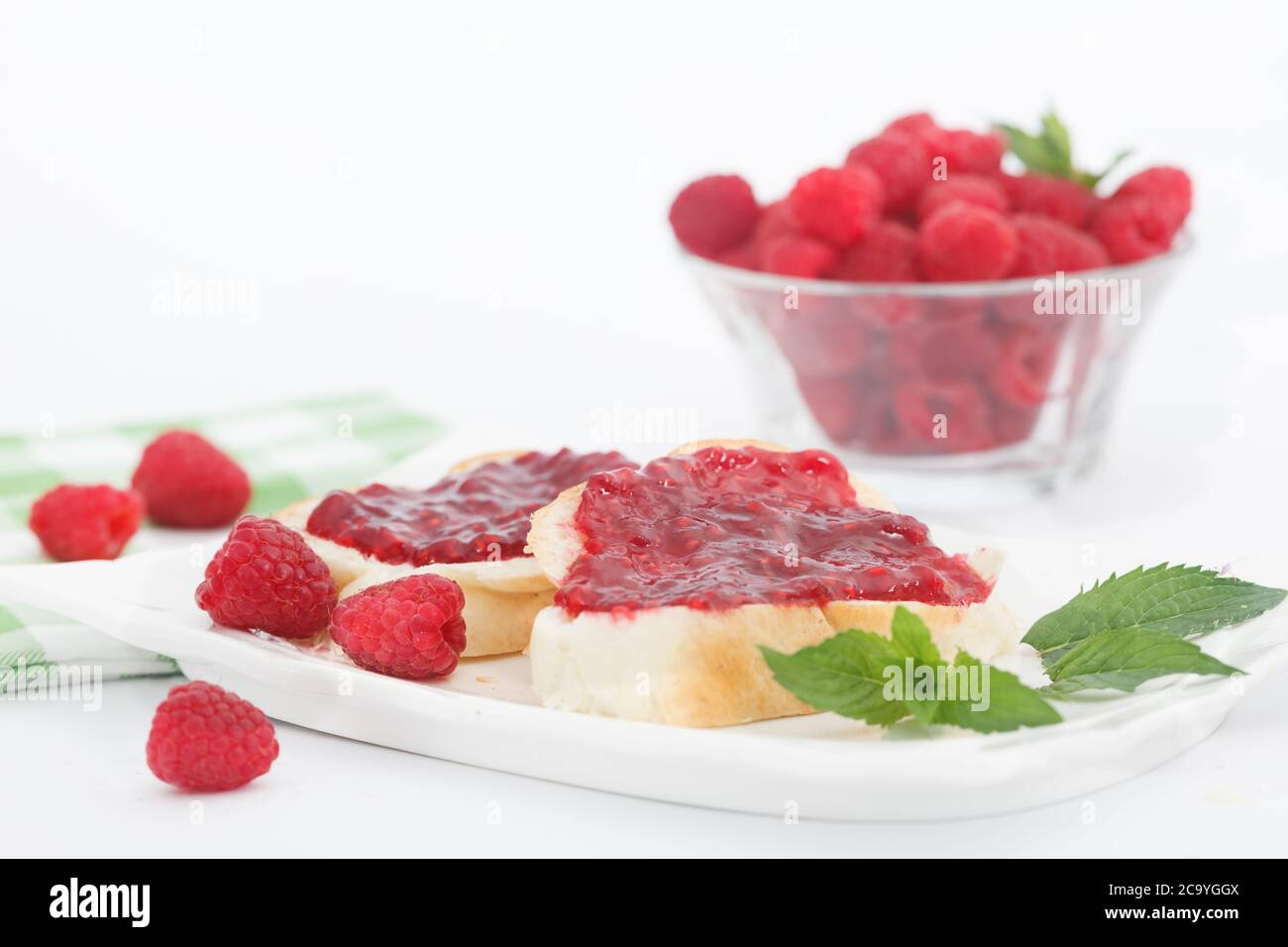 Raspberry jam with fresh raspberries and bread slices on white plate ...