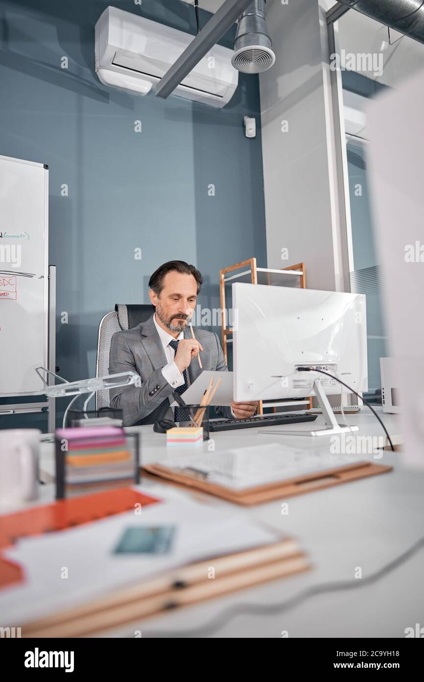 Handsome serious man studying documents at work Stock Photo