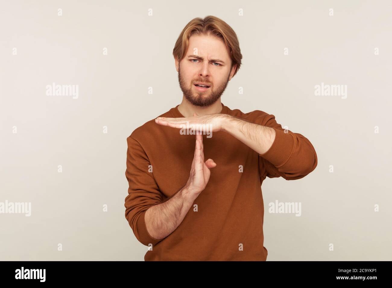 Stop, need pause! Portrait of disgruntled man with beard wearing sweatshirt doing time out gesture, demanding break before deadline, warning of ban. i Stock Photo