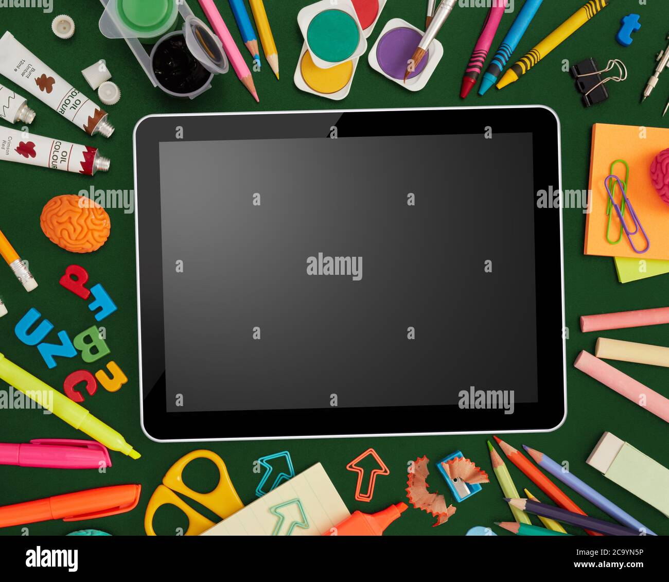 Digital tablet and school supplies on blackboard Stock Photo